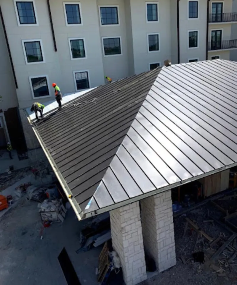 Crew installing standing seam metal roof panels on a commercial project in Pine Castle